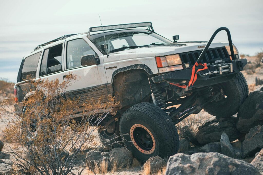 Four-wheel drive vehicle climbing rocky terrain in a desert setting.