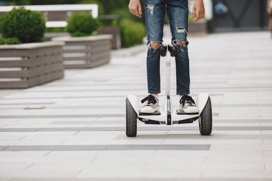 Close-up of young adult riding a Segway hoverboard on an urban walkway, showcasing modern transportation.